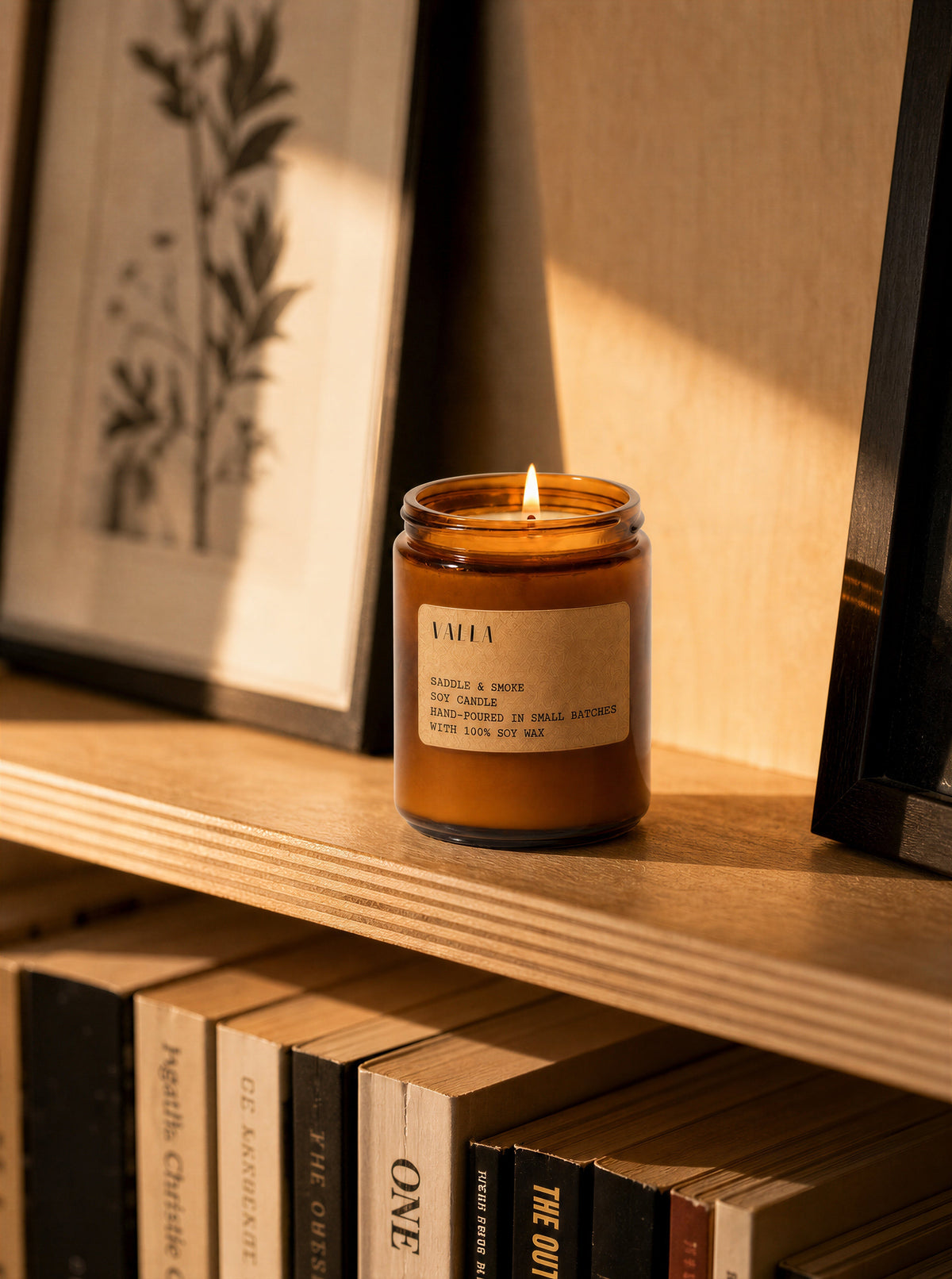 Saddle & Smoke candle on a bookshelf in afternoon light