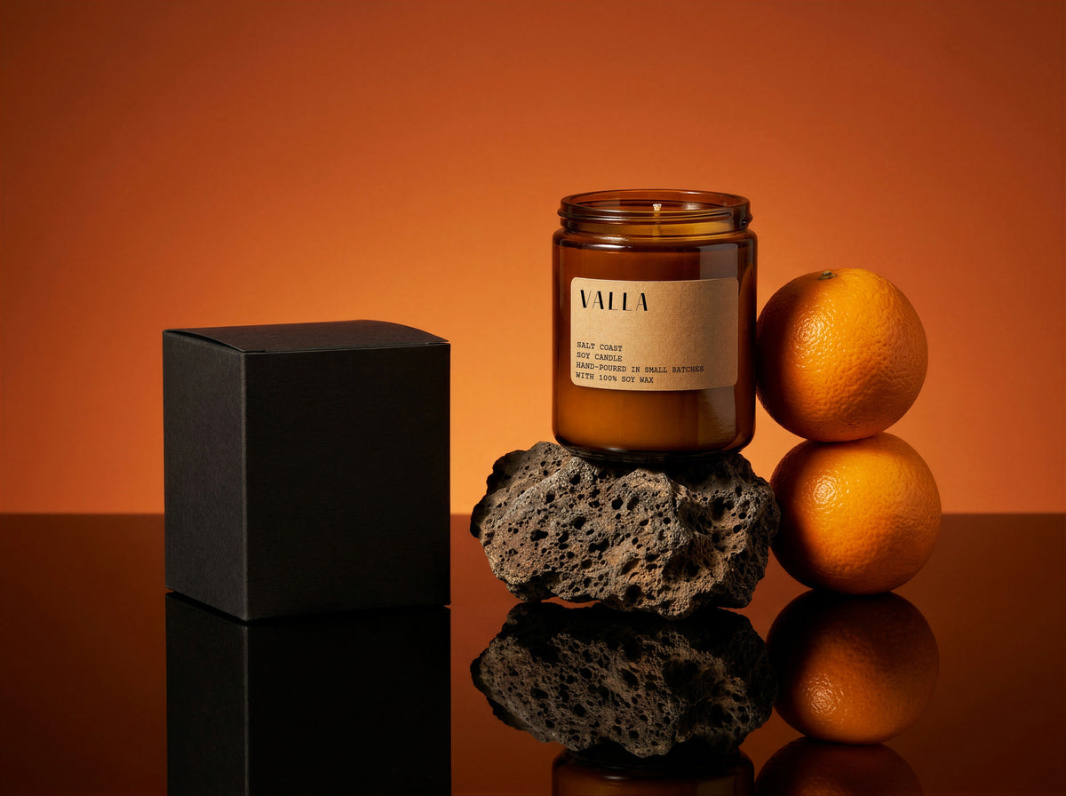A candle beside its box with fresh citrus